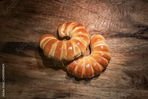 Fresh Golden Crescent Bread Rolls on Rustic Wooden Table.  Freshly baked golden crescent bread rolls with a glossy crust arranged on a rustic wooden tabletop. Warm natural tones, artisan bakery style.