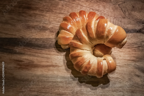 Fresh Golden Crescent Bread Rolls on Rustic Wooden Table.  Freshly baked golden crescent bread rolls with a glossy crust arranged on a rustic wooden tabletop. Warm natural tones, artisan bakery style.