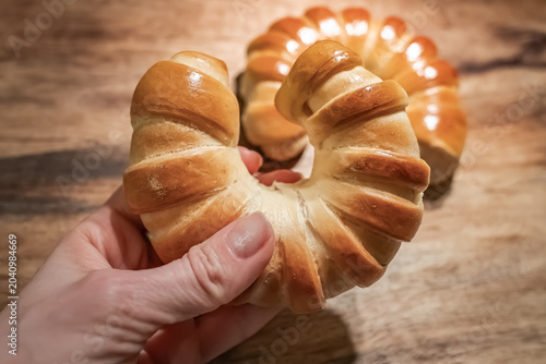 Fresh Golden Crescent Bread Rolls on Rustic Wooden Table.  Freshly baked golden crescent bread rolls with a glossy crust arranged on a rustic wooden tabletop. Warm natural tones, artisan bakery style.