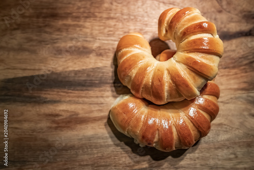 Fresh Golden Crescent Bread Rolls on Rustic Wooden Table.  Freshly baked golden crescent bread rolls with a glossy crust arranged on a rustic wooden tabletop. Warm natural tones, artisan bakery style.