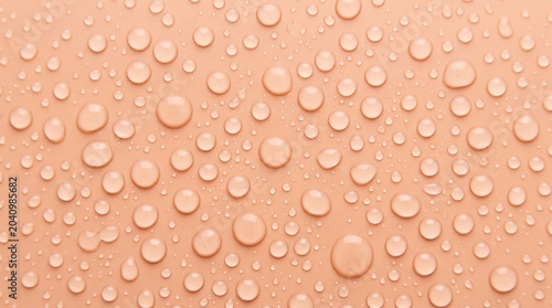 Vibrant Water Droplets Spread Across a Smooth Peach Background, Creating a Fresh and Clean Texture.