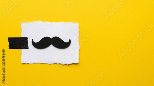 Bright Yellow Background Features Black Mustache Symbol on White Paper for Movember Men's Health Awareness