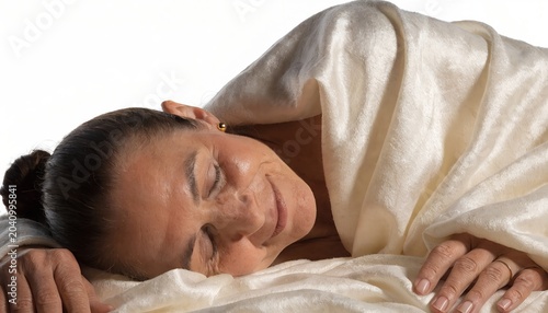 Serene mature woman sleeping peacefully under soft white blanket