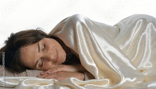 Peaceful woman sleeping under a silky white blanket in soft lighting