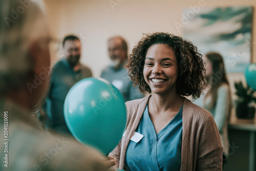 Smiling Biracial Nurse in Blue Scrubs Holding Teal Balloon, Soft Focus Hospital Setting with Abstract Art.