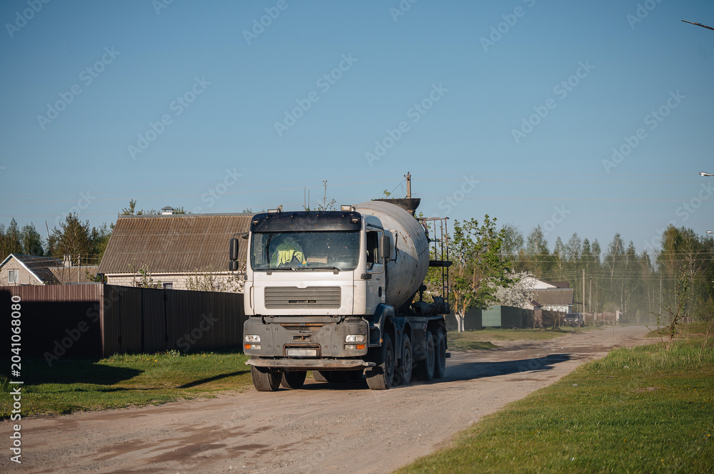 Obraz premium Heavy truck with a concrete cement mixer driving down the city street, construction and infrastructure concept