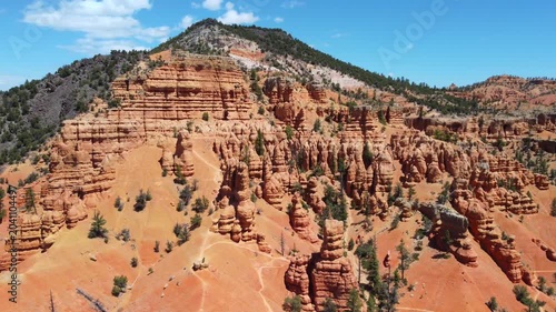 Cinematic drone footage flying over Dixie National Forest in Utah. Stunning aerial view of dramatic red rock spires, hoodoos, and geological formations similar to Bryce Canyon. 