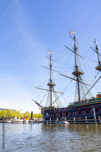The impressive replica of the VOC ship 'Amsterdam' is docked in Amsterdam, Netherlands, under a clear blue sky.