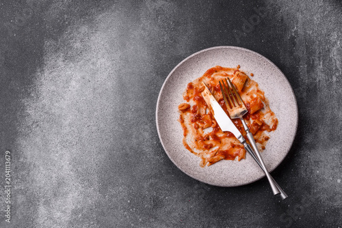 Фотография A dirty plate after a meal with leftover pasta and tomato sauce, cleaning