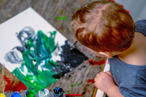 Фотография Overhead view of a toddler observing colorful artwork during a creative learning activity