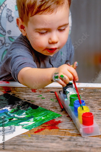Curious young child exploring colors and creativity through painting. Preschool education, artistic development and learning through play concept.