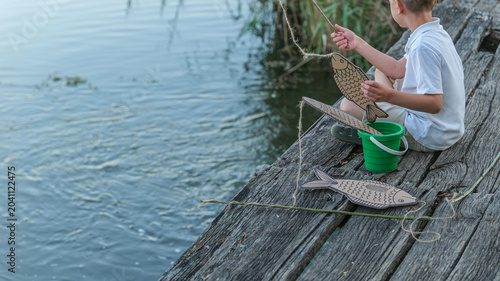 Canvastavla Young boy enjoys a pretend fishing game on a rustic wooden pier by the water