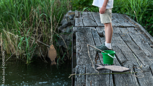 Photography Child's playful fishing attempt with a wooden fish lure on a rustic pier