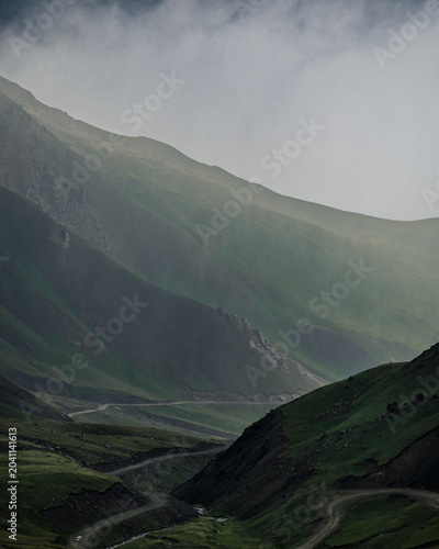 Foto Winding Mountain Road Through a Misty Green Highland Valley