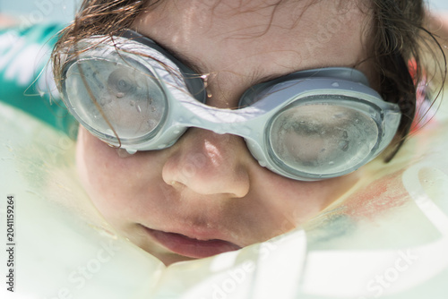 Foto Close-up of an innocent and happy child laughing naturally while swimming on a pool float, capturing the essence of childhood summer holidays