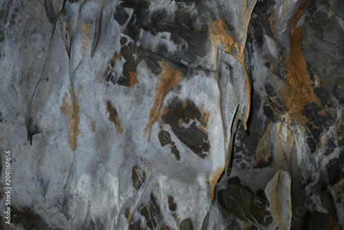 Abstract cave rock formations with colorful mineral deposits, close-up texture of stalactites and underground stone ripples.