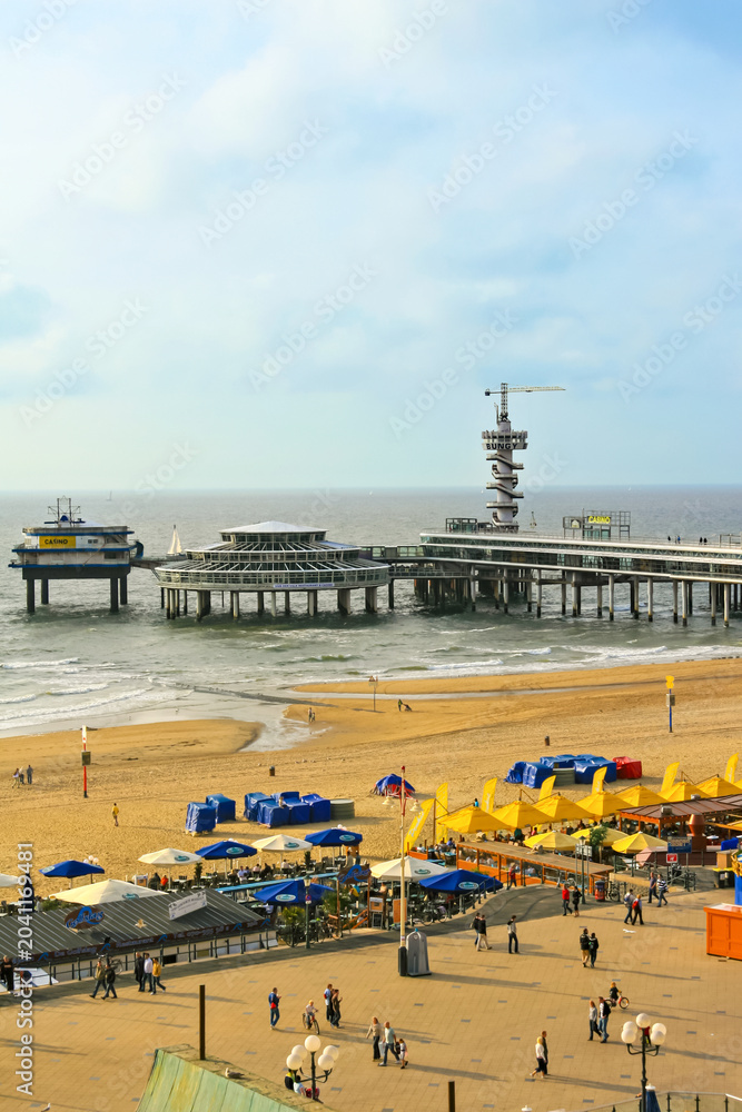 Obraz premium Scheveningen Pier with bungee jumping tower, beach umbrellas and the North Sea coast.