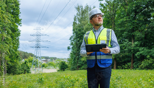 Energy engineer, auditor inspecting power lines in spring forest. Power grid maintenance and inspection. Ecologist assessing infrastructure impact on spring forest nature. Climate change.