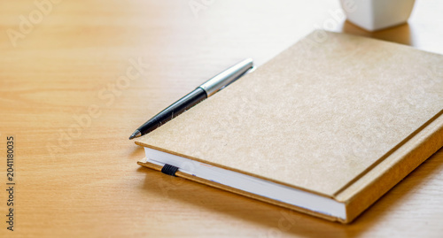 Simple brown notebook and pen on wood