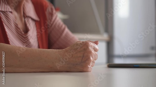 Close-up of an elderly woman slamming her fist on the table in anger