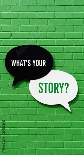 Two Speech Bubbles Asking Whats Your Story Against a Green Brick Wall.
