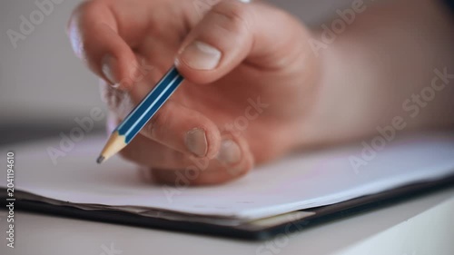 Paramedic documenting home patient notes, closeup hand holding pencil over notebook, visible fingernails and graphite tip, soft natural lighting, blurred residential background, focused checklist