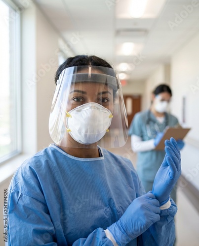 PPE healthcare worker adjusting gloves in a calm hospital corridor