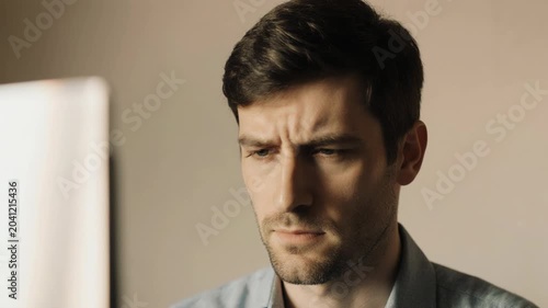 Static close up tilt of man reacting to computer screen at office desk interior during daytime
