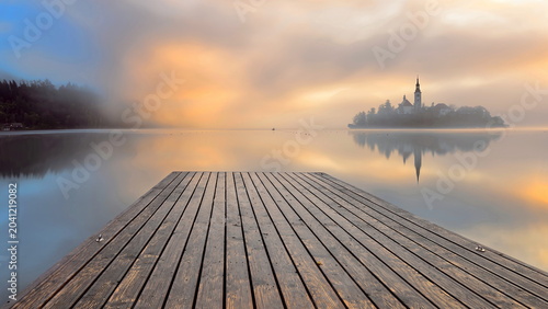 Photos Reddish, thick fog sunrise over the Assumption of Mary church on Bled island, barely visible from Velika Zaka pier across Lake Bled