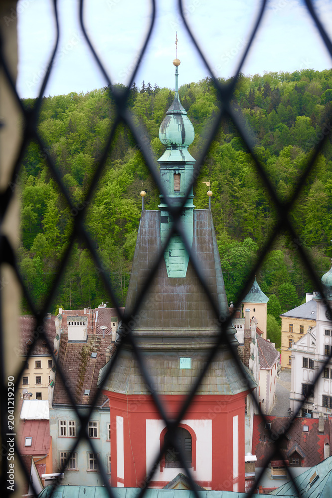 Obraz premium View from a castle window through a forged iron grate to an ancient tower.