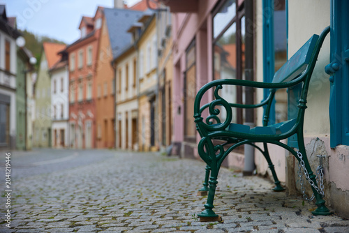 Empty cobblestone street with colorful houses and bench