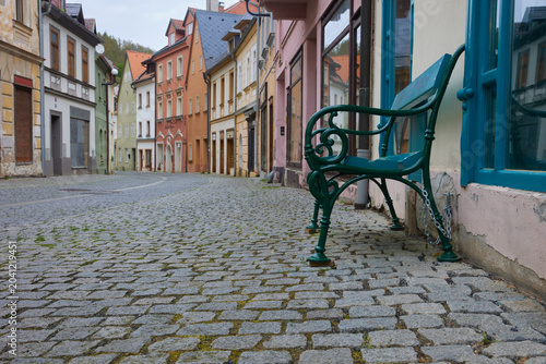 Empty cobblestone street with colorful houses and bench