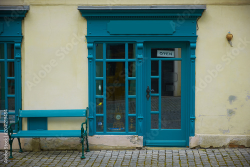 Vintage shop front with turquoise door and bench.