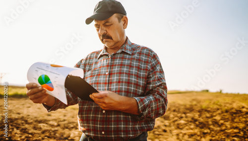 Photos An experienced farmer works in a field with a tablet in hand