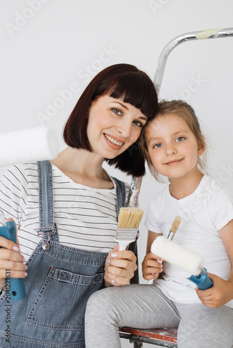 Fotografia A smiling mother and her young daughter bond while holding painting tools, ready