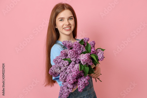 Teenage girl with bouquet of lilac flowers on pink background