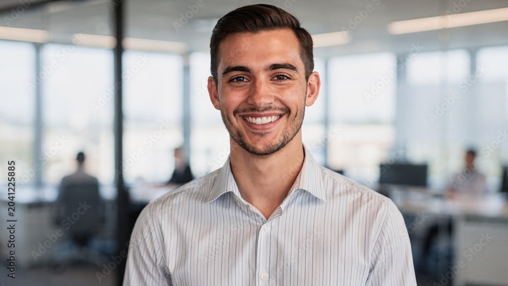 Obraz premium Friendly male employee portrait in contemporary office, smiling professional with confident expression representing business success and workplace achievement