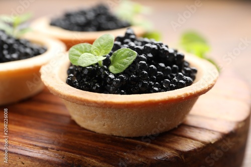Obraz na płótnie Tasty tartlets with black caviar on wooden table, closeup