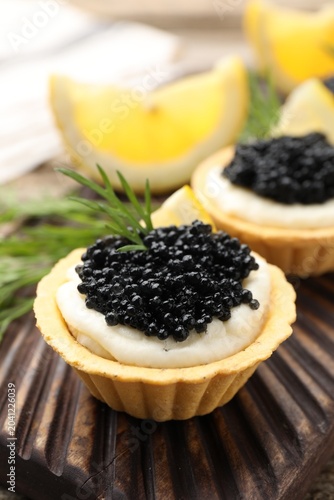 Canvastavla Tasty tartlets with black caviar, cream cheese, dill and lemon on table, closeup