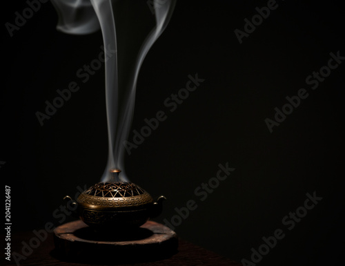 Incense aroma sticks in vintage box with white texture smoke on black background with copy space