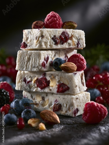 Stacked high protein frozen dessert bars feature berries and nuts, showcasing a healthy treat option with rich textures and shadows