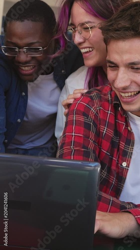 Group of diverse students celebrating success on laptop