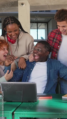 Group of excited students celebrating success with laptop