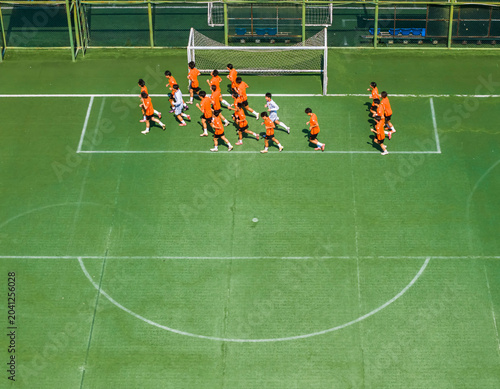 Konstfotografi Aerial view of children in orange jerseys running across the soccer field during soccer practice at a sports park in Wuhan, China