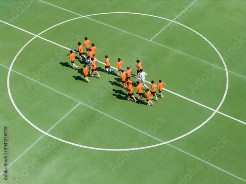 Aerial view of children in orange jerseys running across the soccer field during soccer practice at a sports park in Wuhan, China.