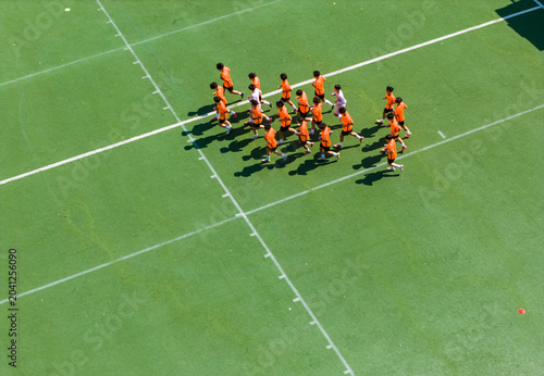 Canvas Print Aerial view of children in orange jerseys running across the soccer field during soccer practice at a sports park in Wuhan, China