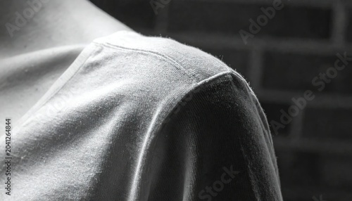 Black and White Close Up of Person Wearing Soft Shirt Near Dark Brick Wall