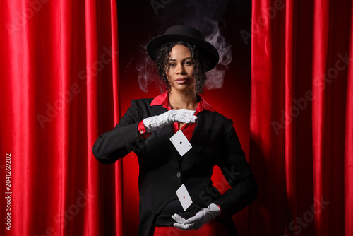 Bild auf Leinwand Young African-American magician showing magic trick with flying cards near red c