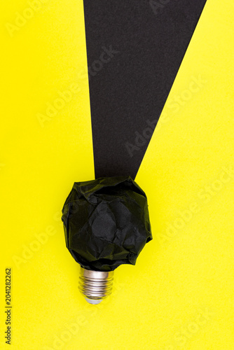 Fotografie Black Paper Light bulb with Dark Beam on Yellow Paper Background
