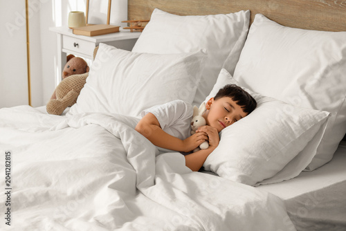 Cute little boy with toys sleeping in bedroom